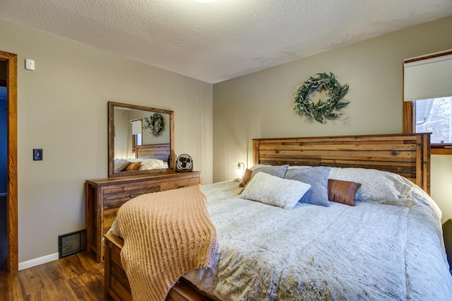 bedroom with dark hardwood / wood-style floors and a textured ceiling