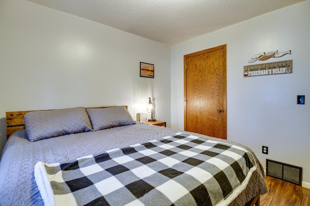 bedroom with dark hardwood / wood-style floors and a textured ceiling