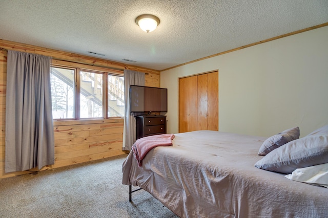 bedroom featuring wood walls, carpet flooring, crown molding, a textured ceiling, and a closet