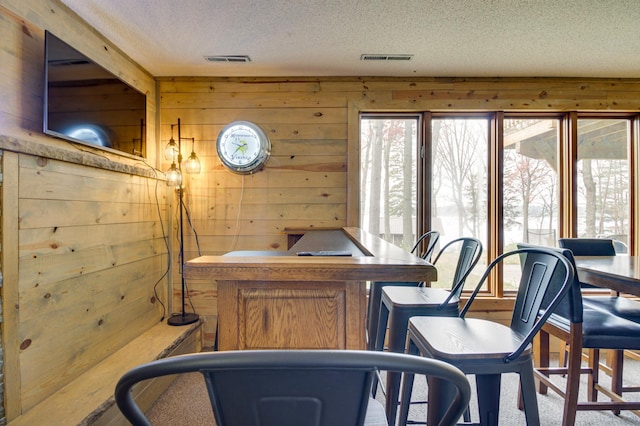 office space featuring plenty of natural light, a textured ceiling, and wood walls