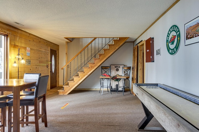 carpeted dining room with crown molding, wooden walls, and a textured ceiling