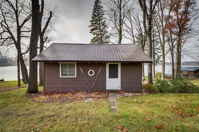 view of front of house featuring an outbuilding, a front yard, and a water view