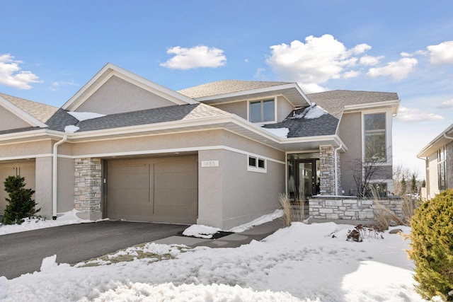 view of front of house featuring aphalt driveway, roof with shingles, stucco siding, stone siding, and an attached garage