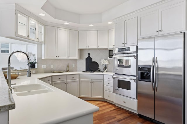 kitchen with light wood finished floors, light countertops, appliances with stainless steel finishes, white cabinets, and a sink