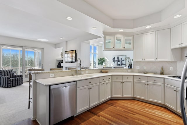 kitchen featuring open floor plan, dishwasher, a peninsula, white cabinetry, and a sink