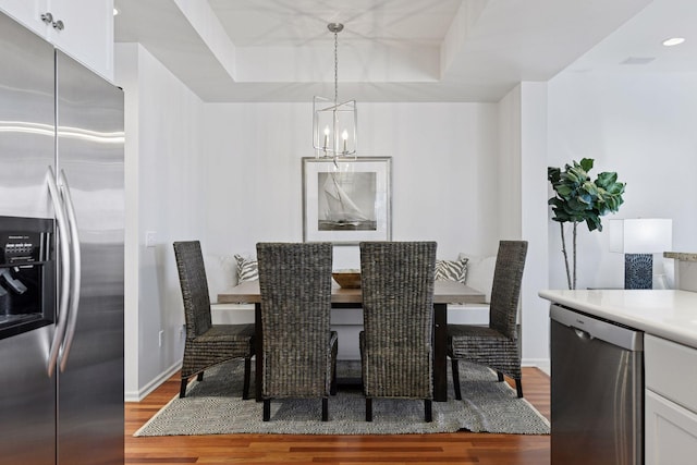 dining room featuring a tray ceiling, baseboards, wood finished floors, and a chandelier