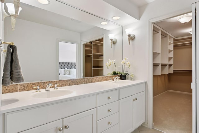 bathroom featuring double vanity, a spacious closet, and a sink