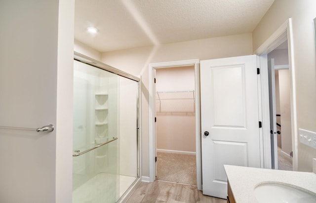 bathroom with hardwood / wood-style flooring, vanity, a shower with door, and a textured ceiling