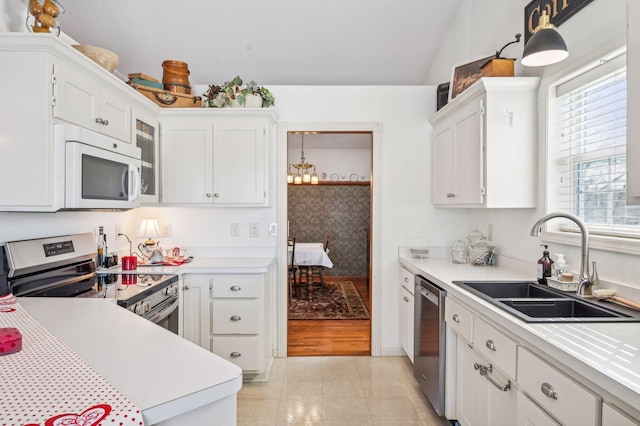 kitchen with stainless steel appliances, white cabinets, pendant lighting, light tile patterned floors, and sink