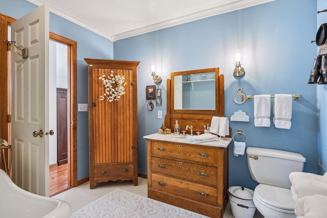 bathroom with toilet, vanity, and crown molding