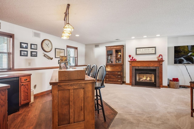 kitchen featuring a textured ceiling, hanging light fixtures, black dishwasher, and a wealth of natural light