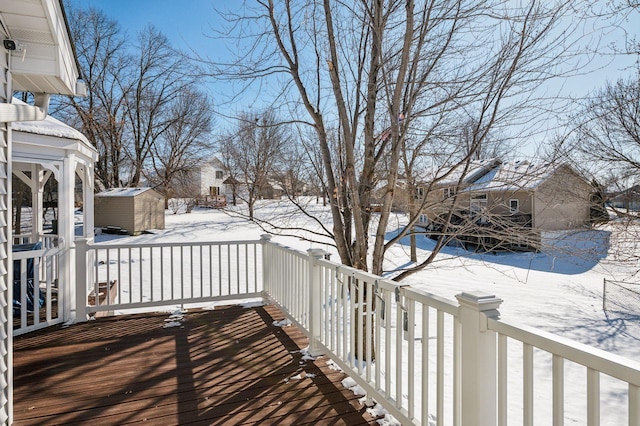 snow covered deck with a storage shed