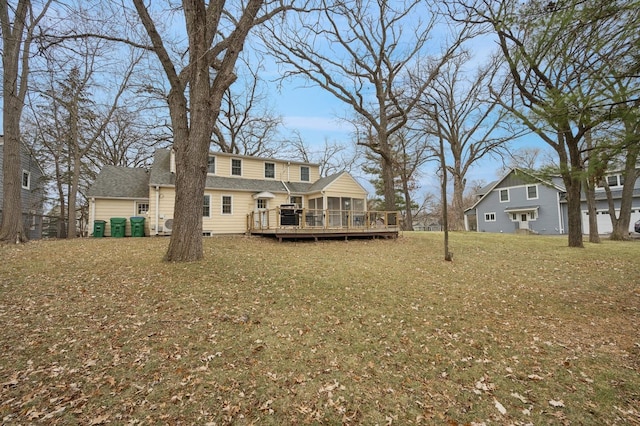 back of property with a yard, a sunroom, and a deck