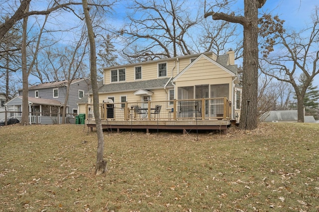 rear view of property with a sunroom, a deck, and a lawn