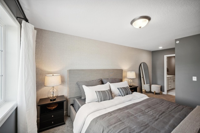 bedroom featuring ensuite bath and light colored carpet