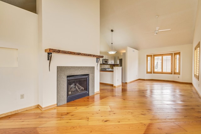 unfurnished living room with ceiling fan, high vaulted ceiling, and light hardwood / wood-style flooring