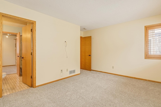 spare room with light carpet and a textured ceiling