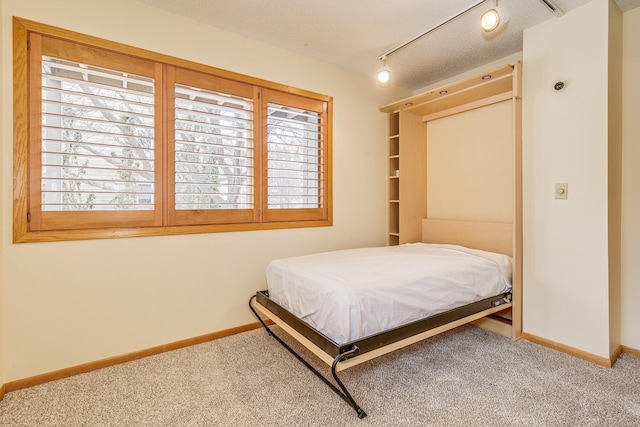 bedroom with carpet, track lighting, and a textured ceiling