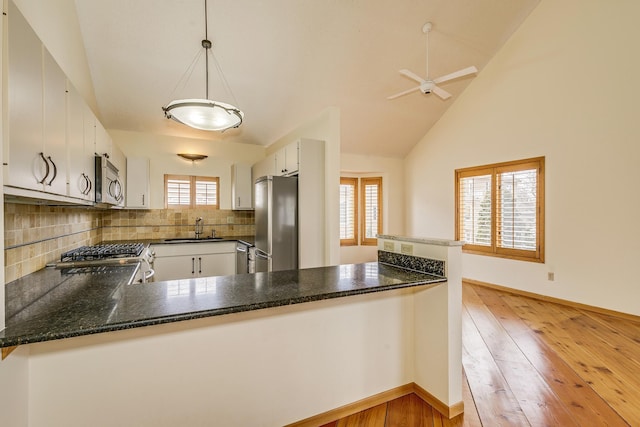 kitchen with appliances with stainless steel finishes, kitchen peninsula, sink, and white cabinets