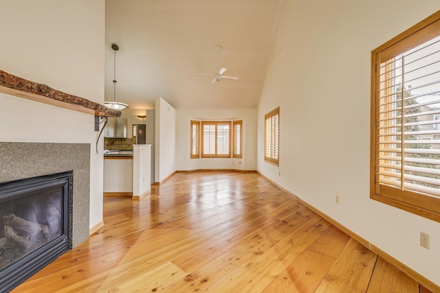 unfurnished living room featuring ceiling fan, high vaulted ceiling, and light wood-type flooring