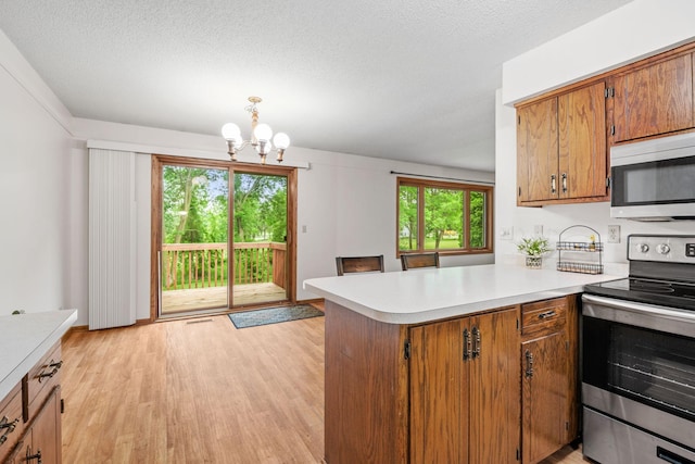 1541 2nd Ave SE, Cambridge, MN 55008 - kitchen with stainless steel appliances, a peninsula, light countertops, brown cabinetry, and a chandelier