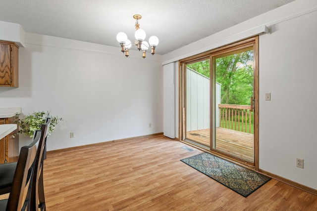 1541 2nd Ave SE, Cambridge, MN 55008 - unfurnished dining area with a chandelier, light wood-style flooring, and a textured ceiling