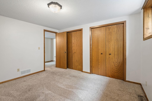 1541 2nd Ave SE, Cambridge, MN 55008 - unfurnished bedroom featuring two closets, carpet flooring, and a textured ceiling
