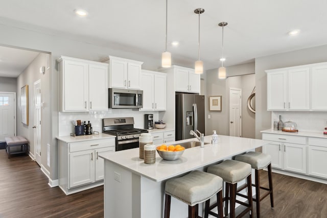 12450 Waterside Ct, Rogers, MN 55374 - kitchen featuring stainless steel appliances, tasteful backsplash, dark wood finished floors, a kitchen breakfast bar, and white cabinetry