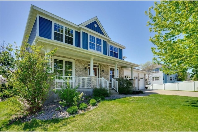 view of front of home with brick siding, fence, a porch, a front yard, and driveway