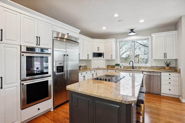 kitchen featuring built in appliances, a breakfast bar, a kitchen island, and white cabinets