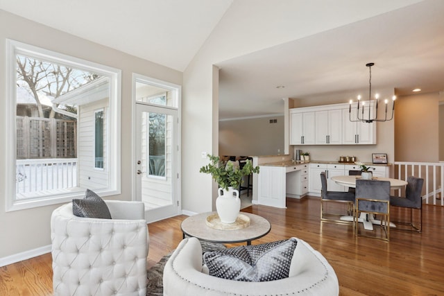 living room with an inviting chandelier, vaulted ceiling, and hardwood / wood-style floors