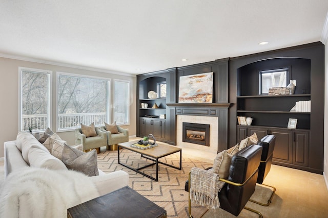 living room featuring built in shelves, ornamental molding, and a tile fireplace