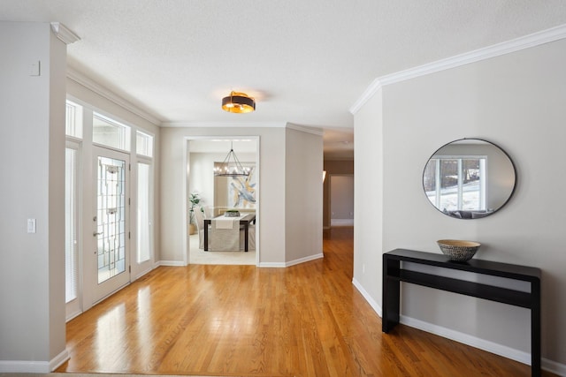 entrance foyer featuring an inviting chandelier, crown molding, light hardwood / wood-style floors, and a textured ceiling