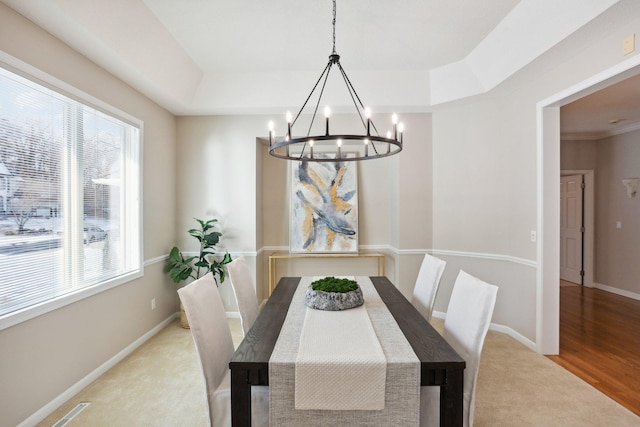 dining space featuring a raised ceiling and light wood-type flooring