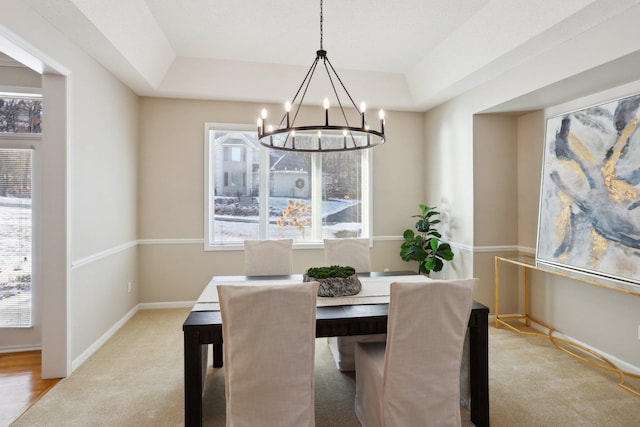 dining room with light carpet, a tray ceiling, and a chandelier