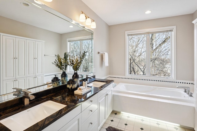 bathroom with vanity, tiled bath, and tile patterned flooring