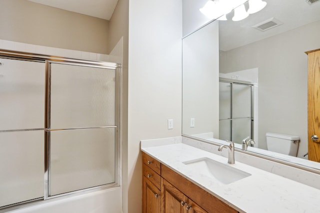 full bathroom with vanity, combined bath / shower with glass door, and toilet