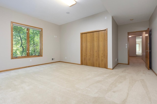 unfurnished bedroom with multiple windows, light carpet, and a closet