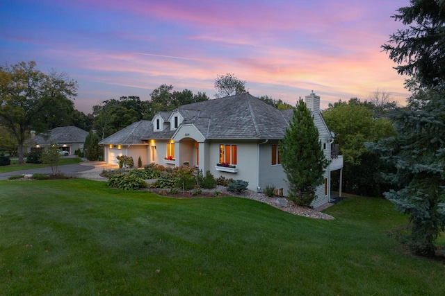 french country inspired facade featuring a yard and a garage