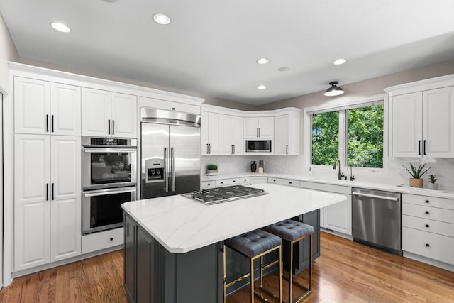 6229 Morningside Cir, Eden Prairie, MN 55344 - kitchen with built in appliances, a kitchen island, white cabinets, a breakfast bar, and recessed lighting