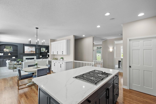 6229 Morningside Cir, Eden Prairie, MN 55344 - kitchen featuring light wood-style floors, white cabinets, stainless steel gas stovetop, crown molding, and light stone countertops