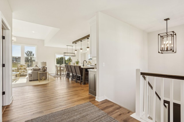 hallway with sink, hardwood / wood-style floors, and a notable chandelier