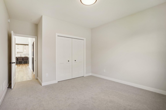 unfurnished bedroom with light colored carpet and a closet