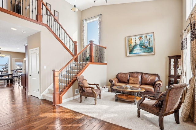 living room with a towering ceiling, stairway, and wood finished floors