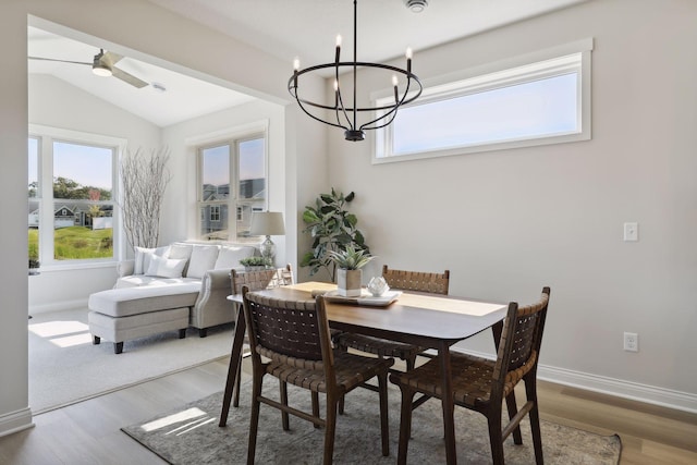 dining room with lofted ceiling, a healthy amount of sunlight, baseboards, and wood finished floors