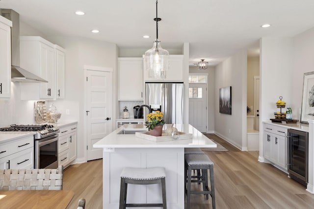 kitchen featuring light countertops, appliances with stainless steel finishes, white cabinets, a sink, and an island with sink