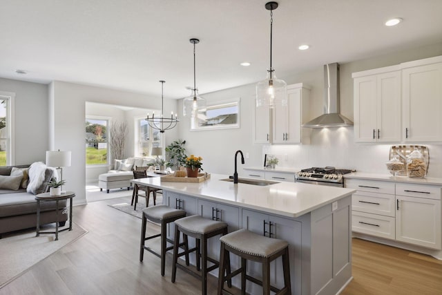 kitchen featuring wall chimney range hood, open floor plan, a sink, and light countertops