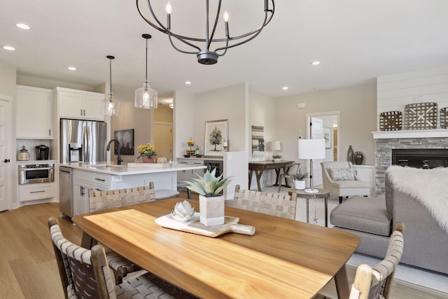 dining space featuring light wood-style floors, recessed lighting, and a stone fireplace