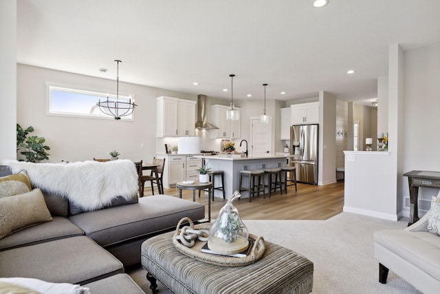 living area with recessed lighting, light carpet, baseboards, and an inviting chandelier