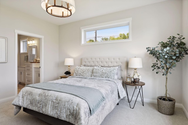 carpeted bedroom with ensuite bathroom, an inviting chandelier, and baseboards